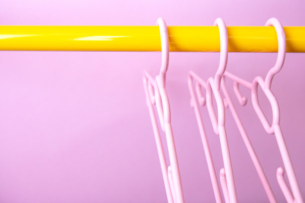 一套三个粉色衣架挂在架子上，以粉色为背景图片下载