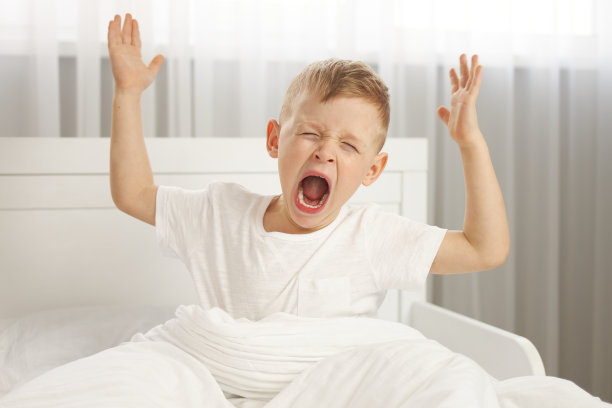 这个可爱的小男孩醒来时伸开了胳膊，打了个呵欠。图片下载