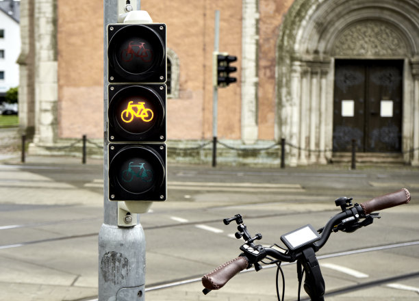 自行车车把旁边的交通灯为自行车显示黄灯，概念自行车旅游在市中心图片下载