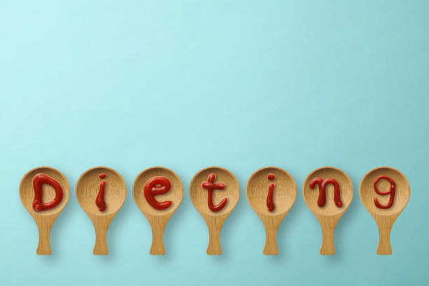 “节食”这个词写在一排木勺上，背景是淡蓝色图片下载