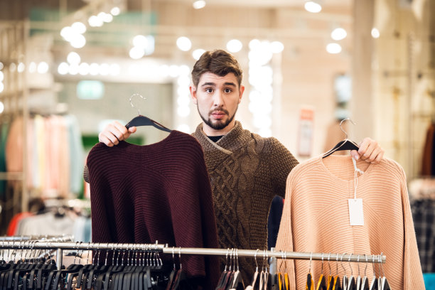 选择哪一个选择的概念。一个十几岁的孩子，在百货公司的栏杆旁有两件毛衣图片下载