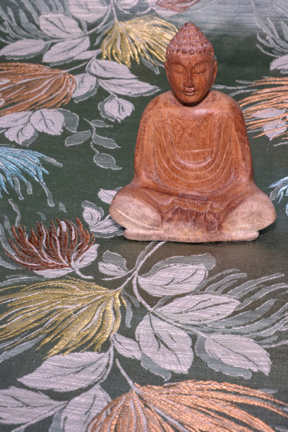 鲜花背景上的木制佛像特写图片下载