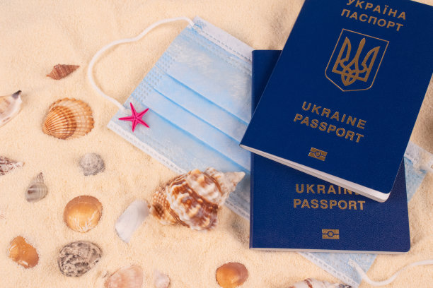 乌克兰生物识别护照和面罩在海滩上，周围有贝壳。2019冠状病毒病大流行期间的暑假。旅游的概念。有选择性的重点图片下载