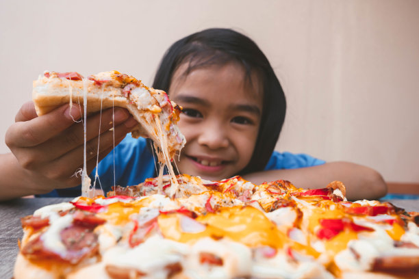 披萨和孩子的概念，披萨片的一部分在手吃，快餐小吃美味可口的桌子上，许多奶酪在表面订购送货图片下载