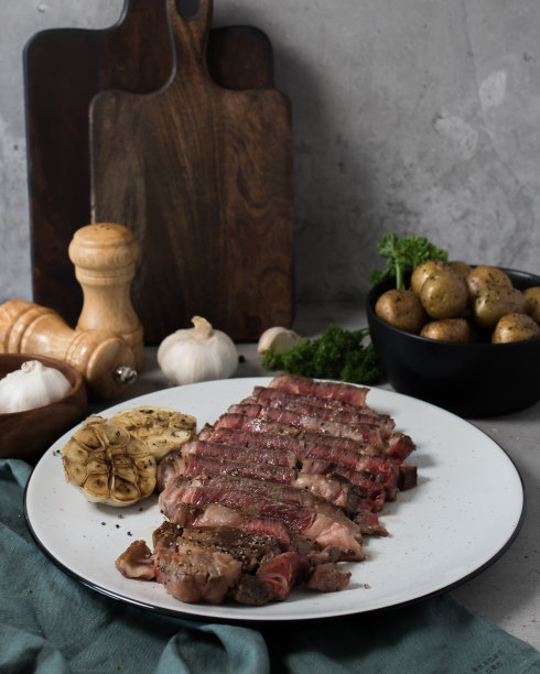 三分熟的牛排配大蒜，土豆和胡椒图片下载