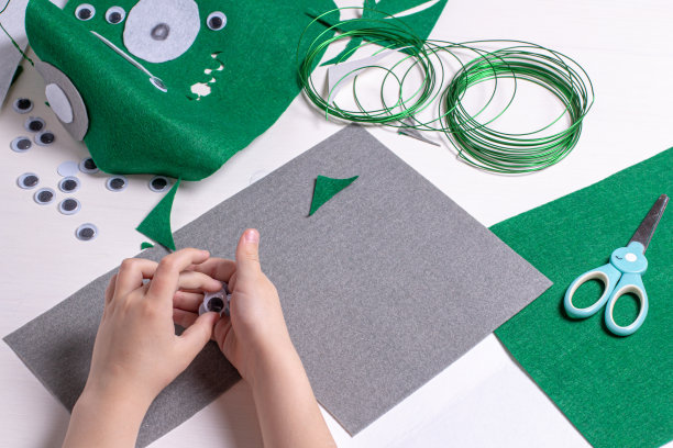 一个孩子的手正在做一个外星人面具的作业。工艺工具，对象和配件的创造力。图片下载