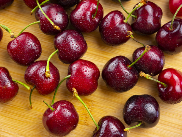 樱桃的背景。分散樱桃水果。把樱桃滴在竹板上。平躺，俯视图。图片下载