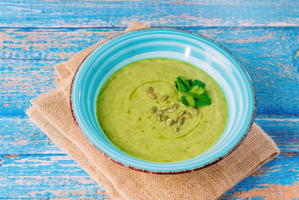 素食奶油花椰菜菠菜汤上面有欧芹叶和南瓜子。青豆汤浓汤原汁照片。图片下载