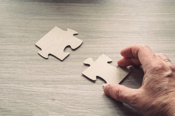 一个男人的手连接在一个木制表面上的谜题的特写。图片下载