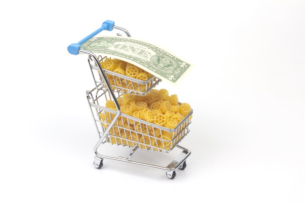 白色背景上有一美元钞票的超市购物篮里的意大利面。面粉制品和烹饪食品图片下载