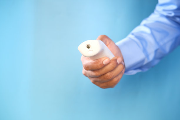 手持红外温度计，在蓝色背景下测量温度图片下载