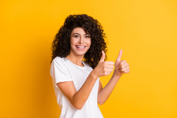 照片肖像快乐的微笑卷曲的女孩显示像手势双手推荐孤立在明亮的黄色背景图片下载