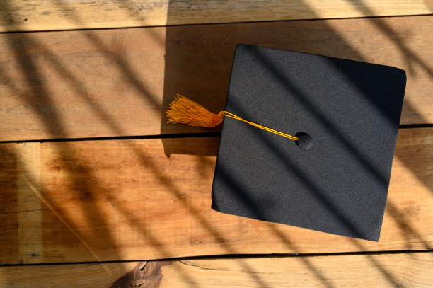 黑色毕业帽放在旧木头背景上图片下载