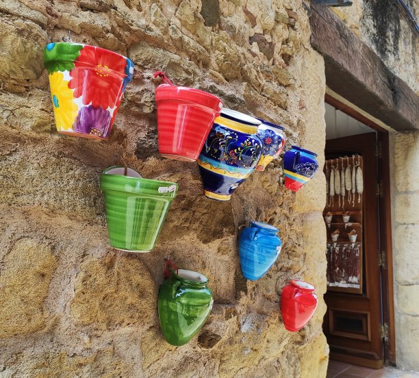 一面石墙上挂着五颜六色的陶瓷花瓶图片下载