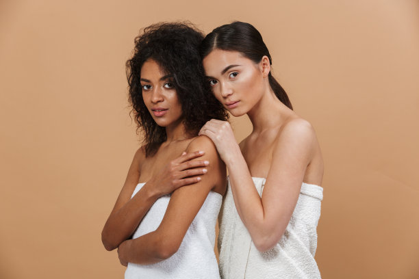 美丽的肖像两个多民族半黑女模特，非洲裔美国和亚洲女性没有化妆，一起摆出孤立的米色背景图片下载