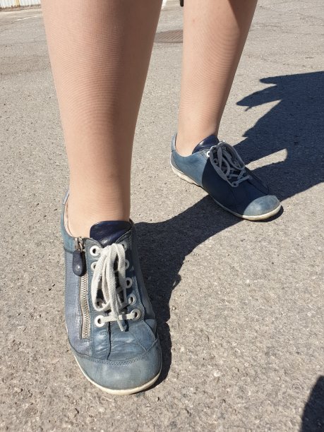 女人的腿在闪亮的米色紧身衣，连裤袜和运动鞋图片下载