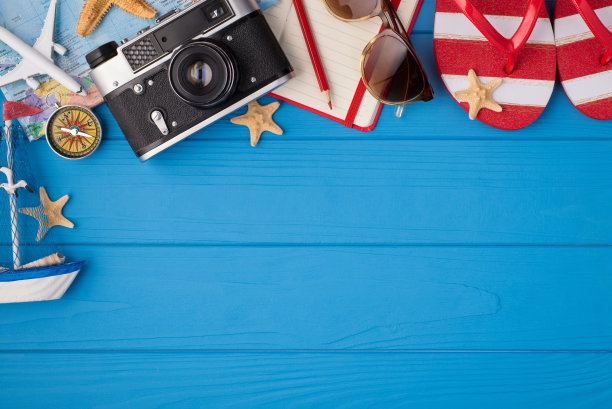 头顶照片的相机，海星，规划师，铅笔，太阳镜，地图，飞机，指南针，船和凉鞋孤立在蓝色木制背景与copyspace图片下载