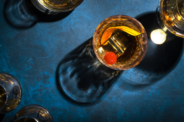 老式酒精鸡尾酒，配以波本威士忌，樱桃酒和橘皮装饰，蓝色桌子，拷贝空间，俯视图，强光图片下载