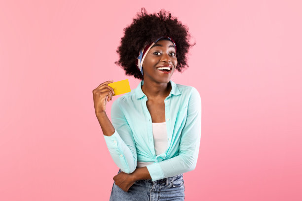 兴奋的非洲裔美国女士持有信用卡在粉红色的背景图片下载