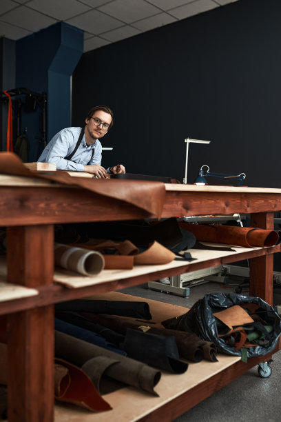 熟练的皮革制造工人在车间裁剪样品图片下载