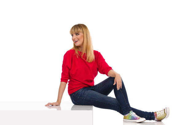 快乐的年轻女子坐在台阶上向后看图片下载