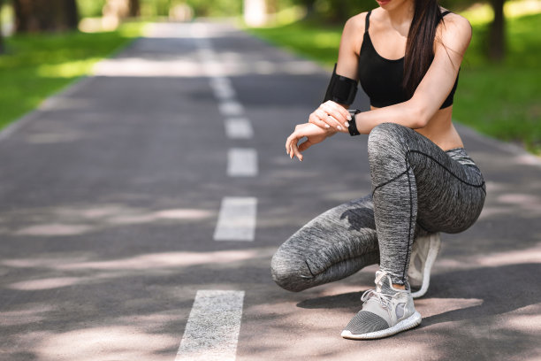 在公园跑步前用智能手表设定计时器的运动女性图片下载