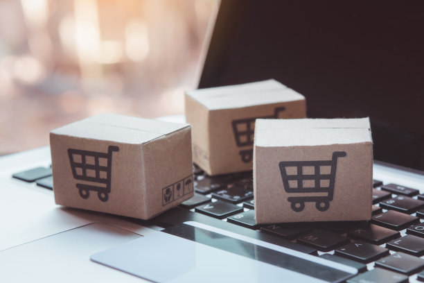 在线购物。信用卡和纸板箱，电脑键盘上有一个购物车的标志。网上购物服务。提供送货上门图片下载