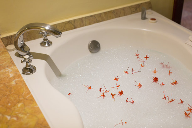 白色浴缸上有泡沫和花瓣的洗澡水，穿着蜜月套装图片下载