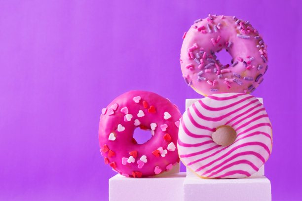 白色的讲台上点缀着不同糖霜的粉色甜甜圈图片下载