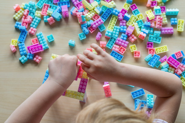 小女孩坐在桌前，玩着五颜六色的积木玩具。图片下载