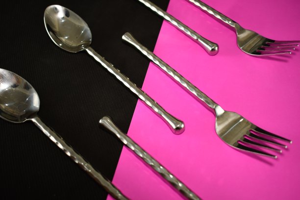 银餐具，叉子和勺子在明亮的黑色和粉红色的餐巾近处美丽的抽象图片下载
