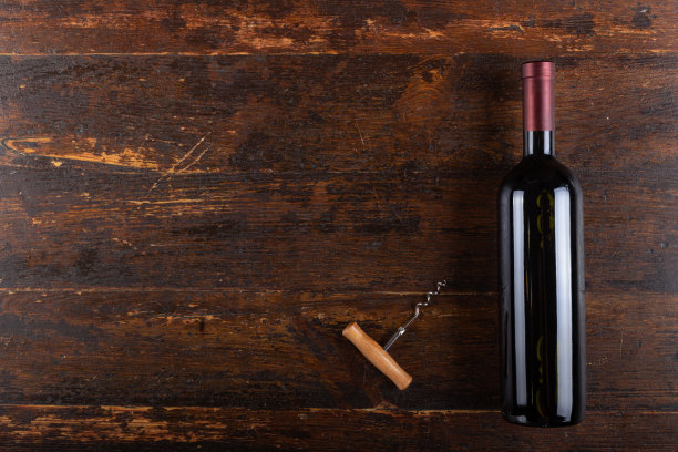 木制背景上的红酒酒瓶和开瓶器。酒精饮料。前视图。图片下载