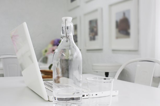 饮用水的玻璃瓶，放在白色的桌子上。图片下载