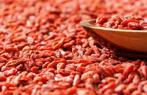 晾干的枸杞放在小木碗里，散落在下面的桌子上图片下载