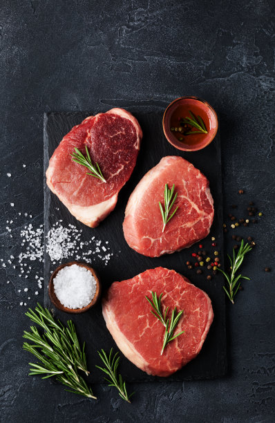 生牛肉放在石板黑盘子上。俯视图平铺。图片下载