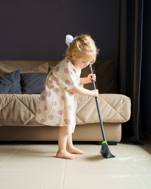 可爱的小女孩在家里用扫帚扫地图片下载