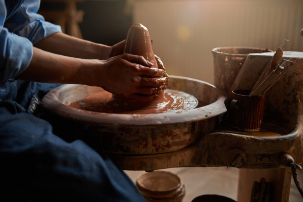 高雅的陶艺家在艺术工作室的陶轮上塑造餐具图片下载