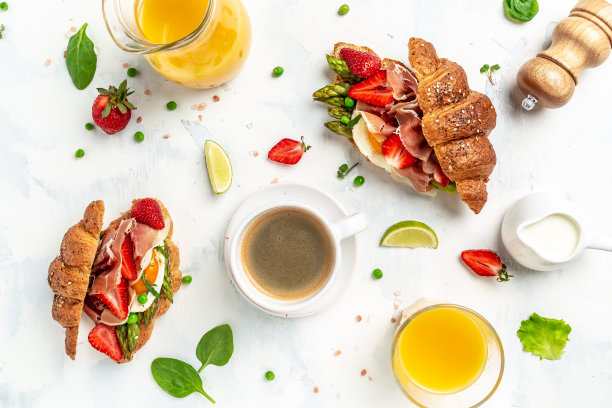 早餐有咖啡，牛角面包有鳄梨，芦笋，火腿，火腿，草莓，单面煎蛋和果汁。横幅格式，俯视图图片下载