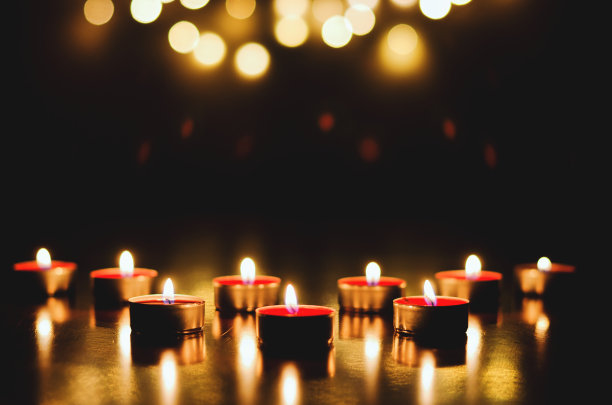 燃烧的蜡烛与节日的散景在黑色的背景。假日和浪漫的概念。祈祷和希望的概念图片下载
