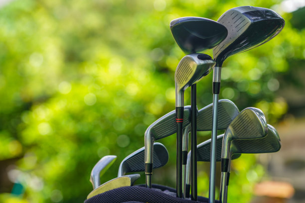 高尔夫球袋和球杆在模糊的高尔夫球场背景前，图片下载
