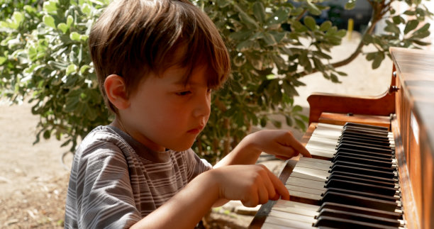 小男孩在户外弹钢琴图片下载