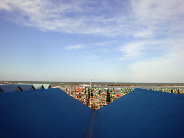 有遮阳伞的海滩，从小屋的屋顶上可以瞥见大海。图片下载