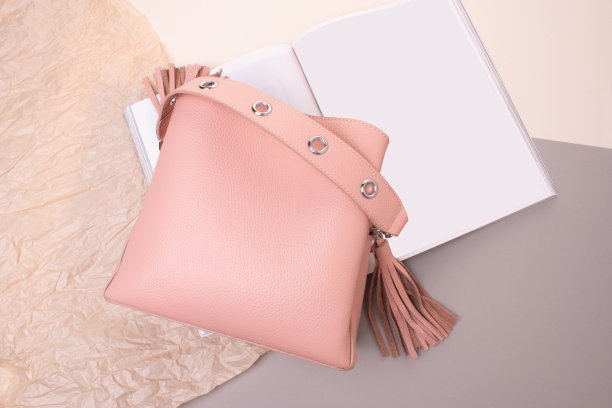 粉色手袋真皮上的灰色和米色纸背景。现代皮包与杂志图片下载