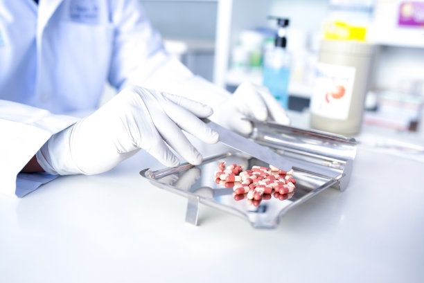 注意看医生的手的图片，抗病毒药物药剂师放在配药托盘上的彩色药丸。图片下载