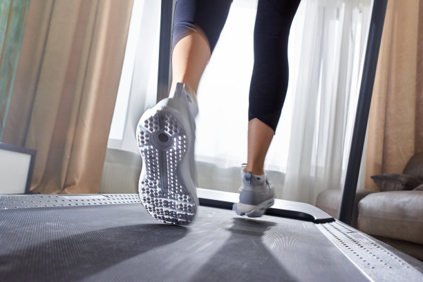 穿着运动鞋在跑步机模拟器上跑步的女孩的腿。图片下载