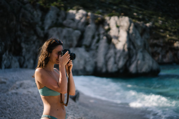 年轻女子在地中海海滩拍照图片下载