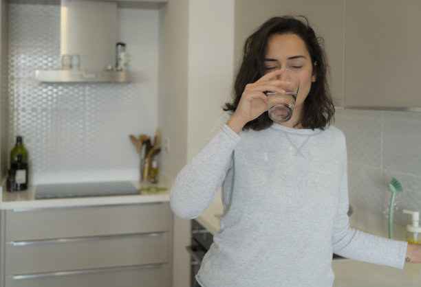 年轻女子在厨房喝水图片下载