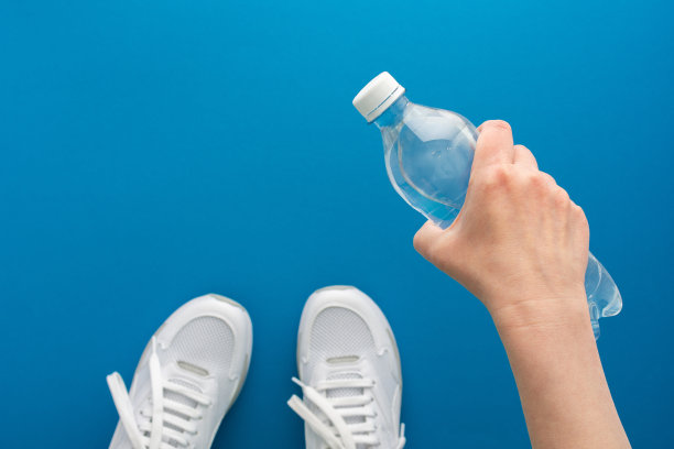 女性手拿一瓶水在健身房图片下载