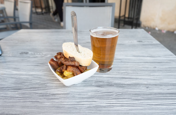 特写照片的一个新鲜的啤酒在一个西班牙酒吧的平台上的猪肉脸颊的一个玻璃杯和开胃酒。图片下载