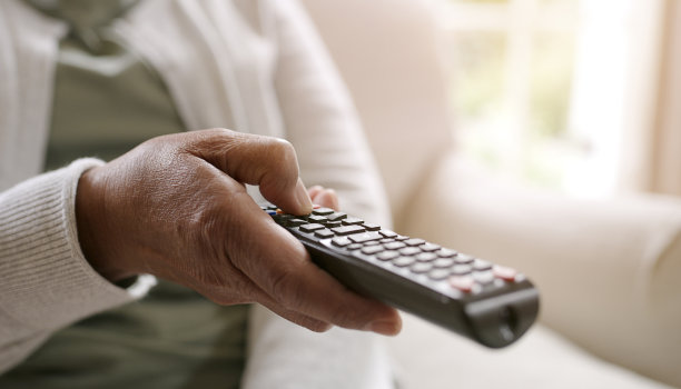 一个女人拿着电视遥控器在家休息的照片图片下载